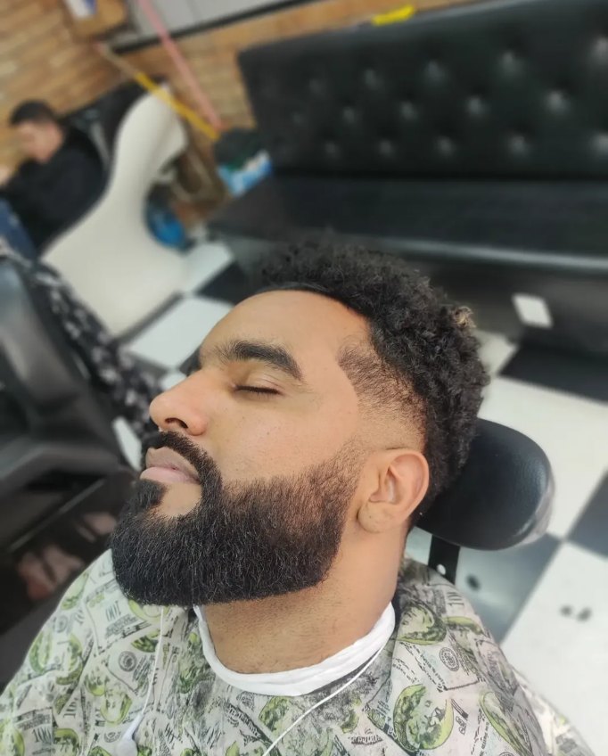 Cliente da GB Barbearia com barba cheia alinhada e degradê finalizado.